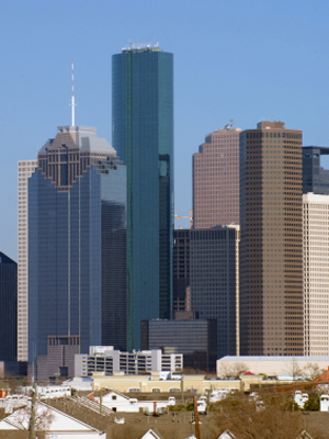 The dense group of modern skyscrapers stand behind a residential area in downtown Houston, Texas, USA.